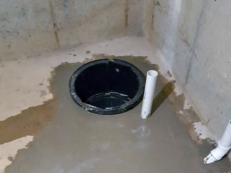 Photo of an unfinished basement with a newly installed sump pump pit 