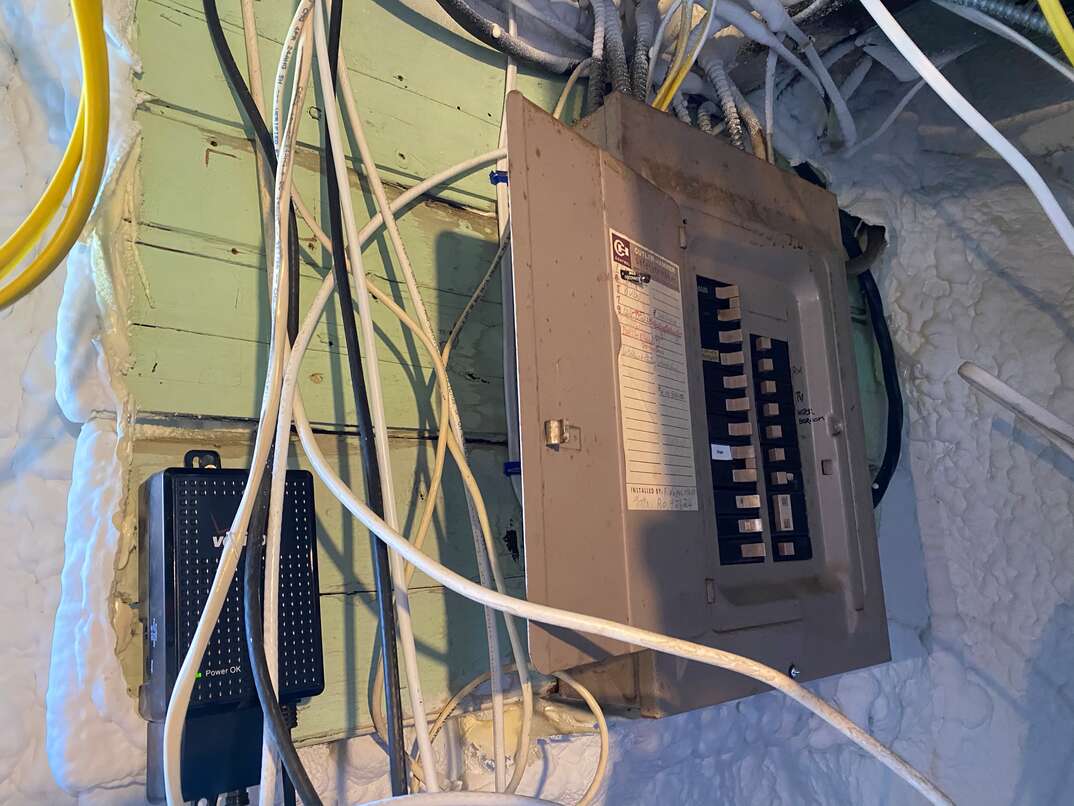 Electrical fuse box in basement with exposed wires