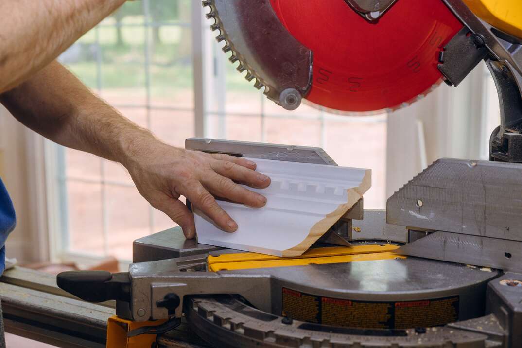 Circular saw with a red blade cutting new crown moulding for renovation