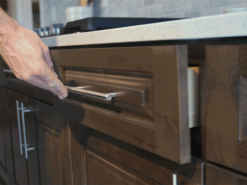 hand pushes a kitchen drawer closed and the soft close mechanism catches the drawer and helps it close