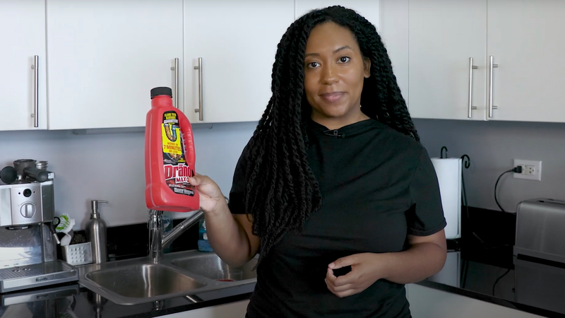 Lauren Leazenby wears a black shirt while holding a red bottle of store bought liquid drain cleaner while standing in a modern kitchen, drano, drain cleaner, woman, Lauren Leazenby, Lauren, kitchen, modern kitchen