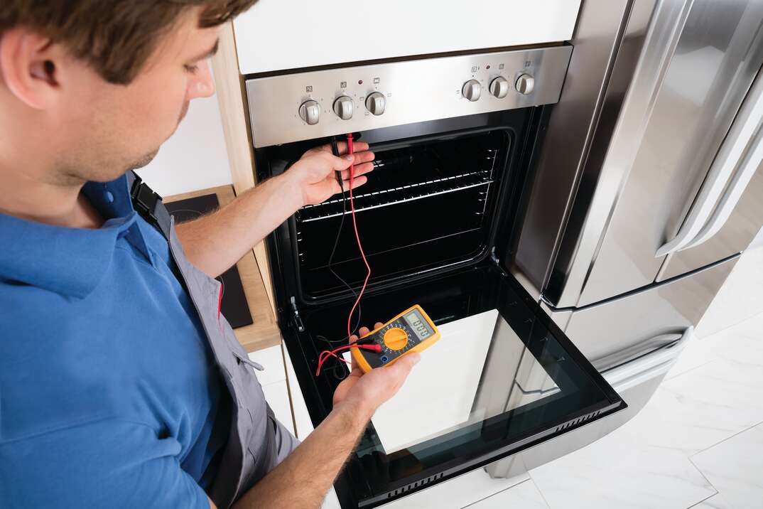 technician checking oven with meter