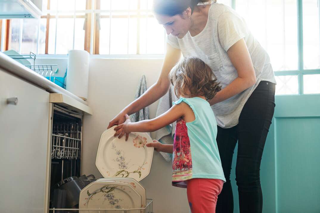 Shot of a mother and daughter busy at a dishwashing machine