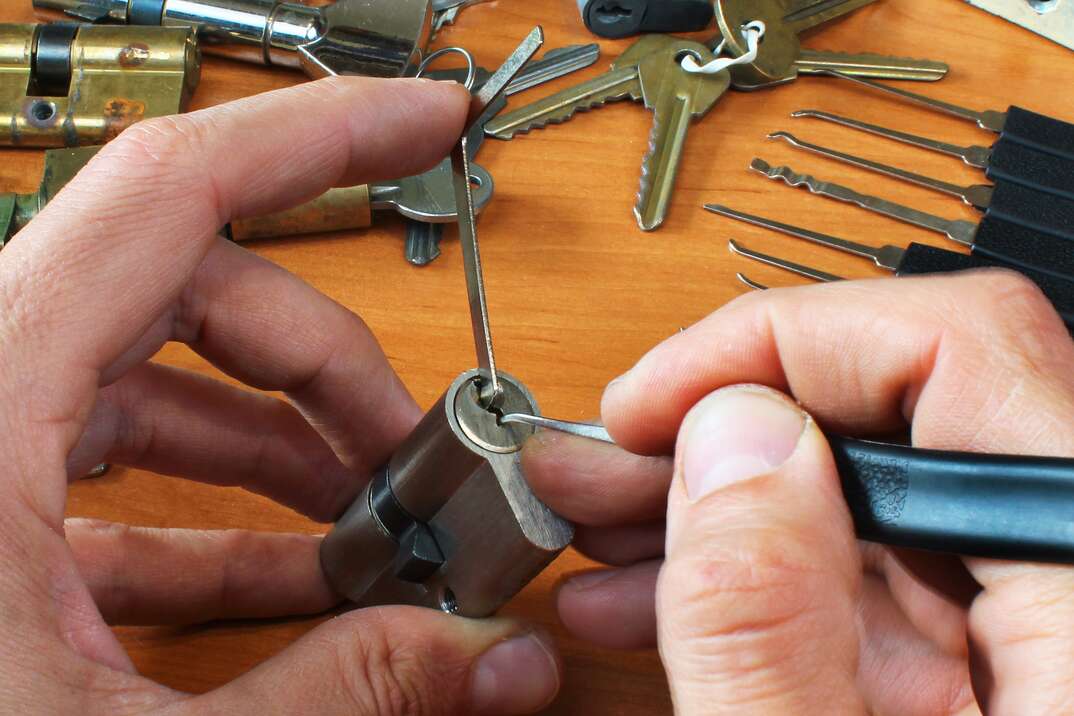 Locksmith picks a cylinder lock with lockpick and tension wrench