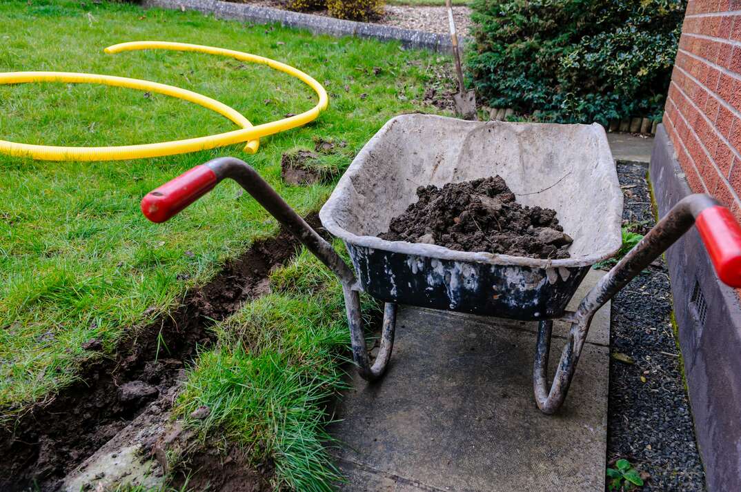 wheelbarrow full of dirt from digging a trench for a french drain