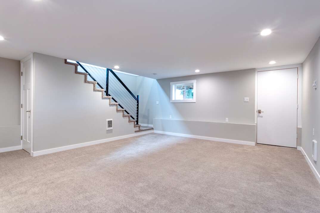 Light grey and spacious basement area with staircase.