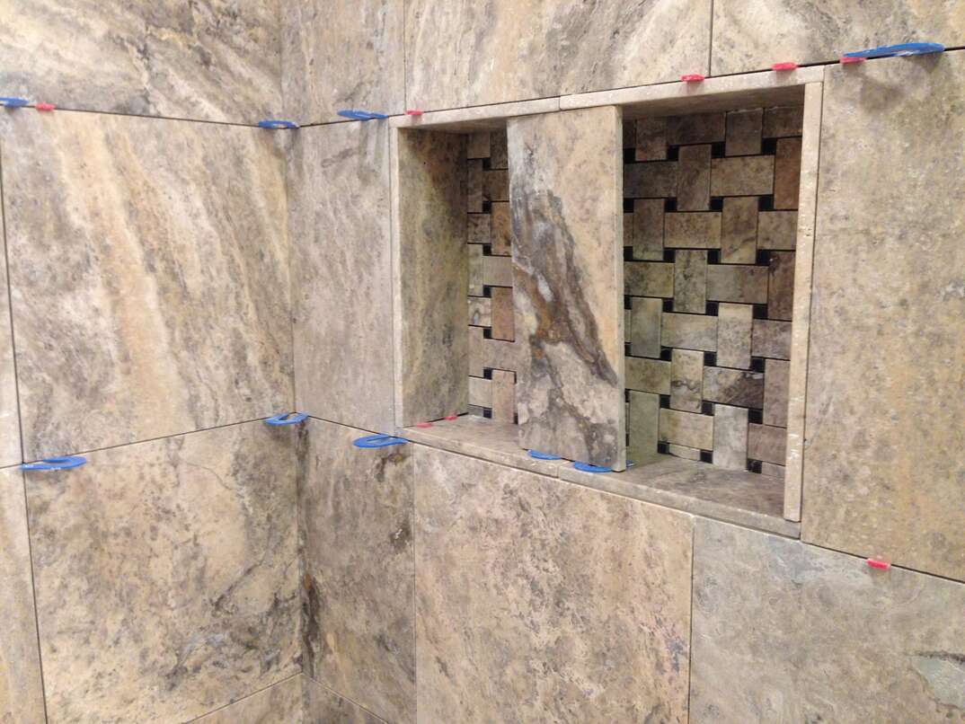 shower with travertine stone tile being installed