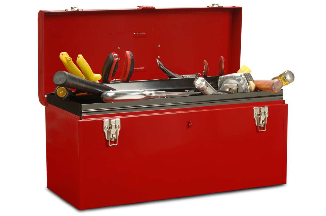 red metal toolbox sits against a white background with its lid open with its overstuffed tools sticking out of the top. A large