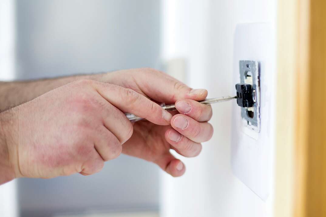 hands with screwdriver fixing wall socket