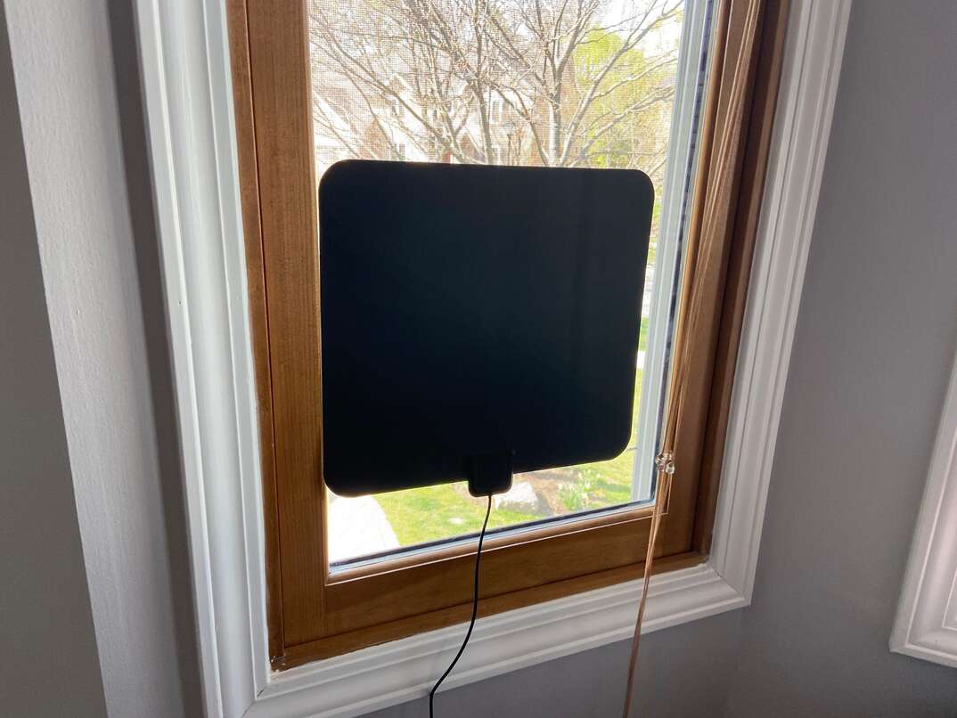 A free-to-air HD antenna suction cupped to a residential window