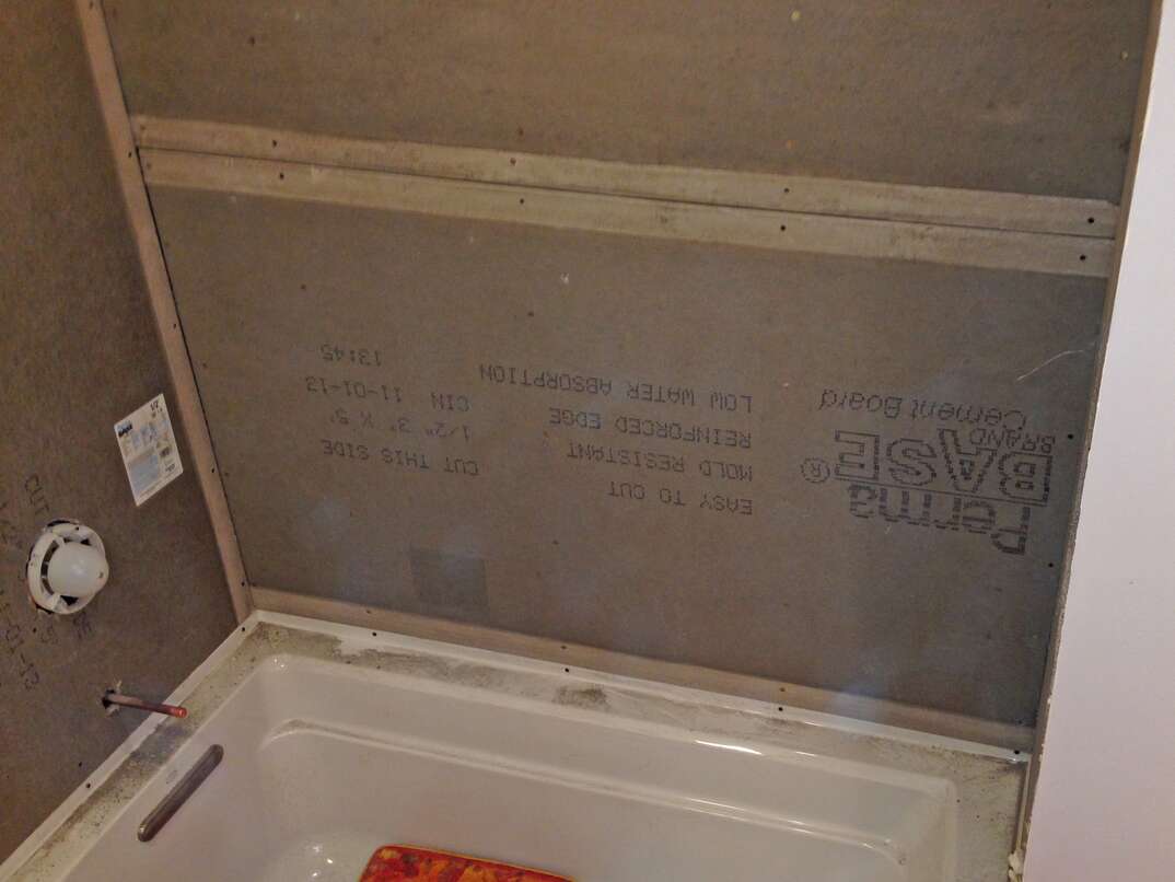 bathtub with travertine stone tile being installed