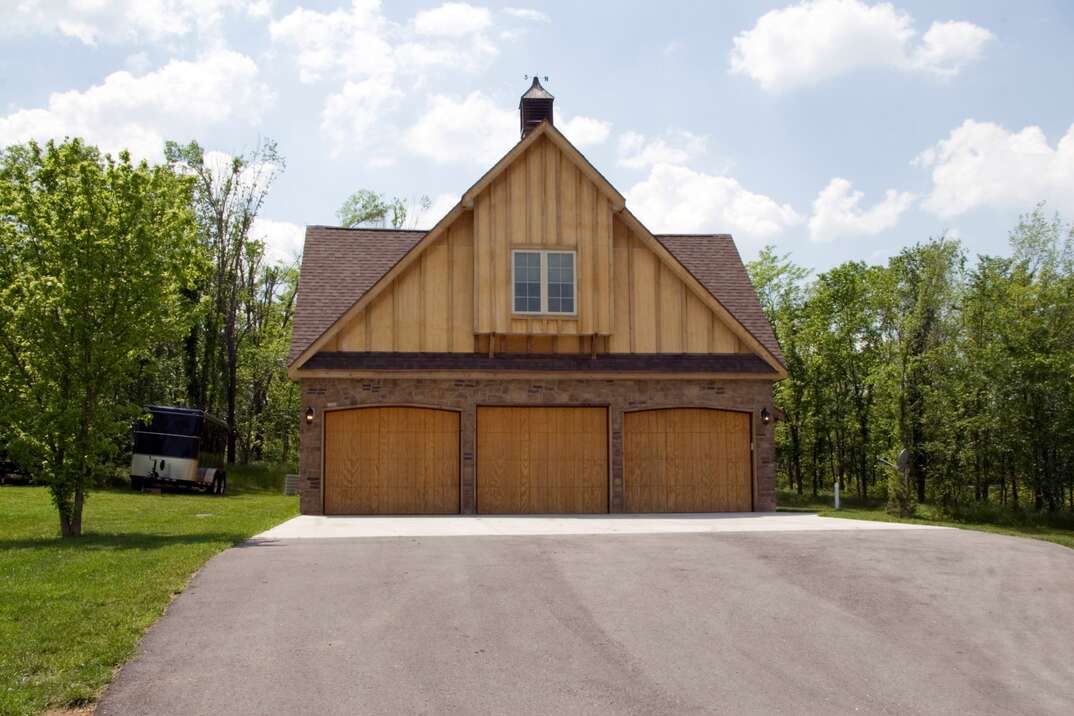 Detached residential three-car garage with a wood and stone exterior