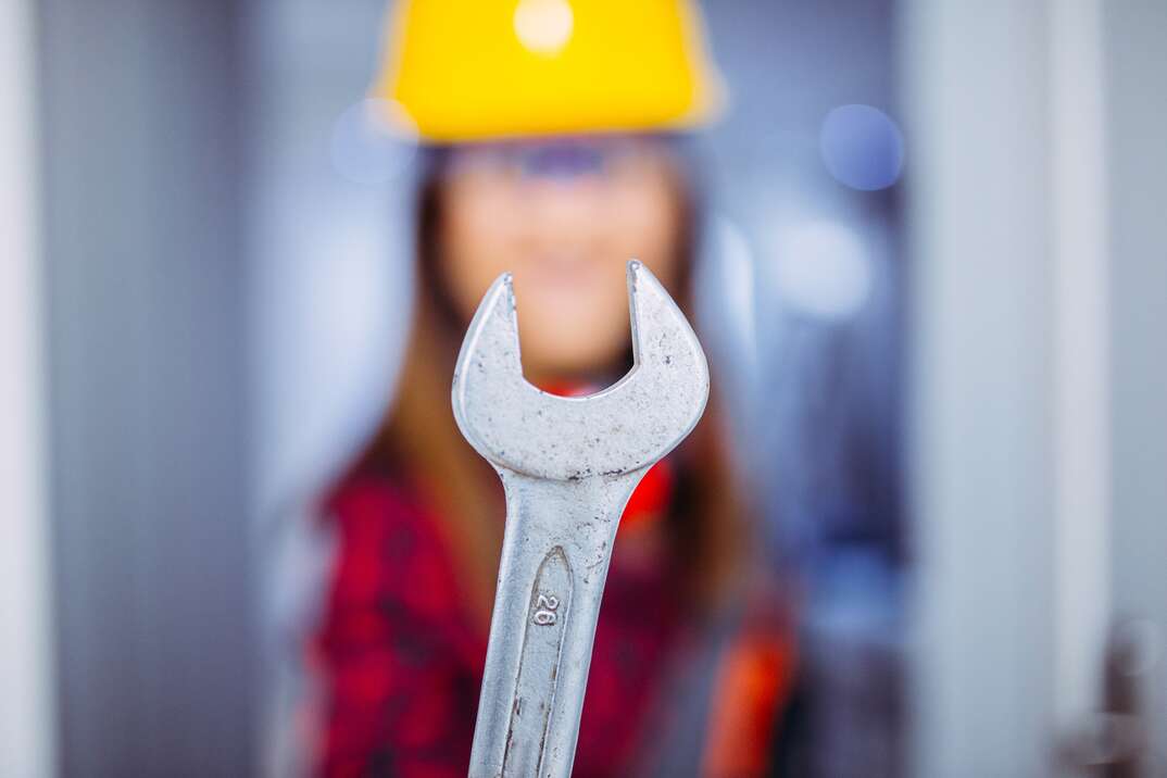 out of focus female worker holds up her weathered wrench