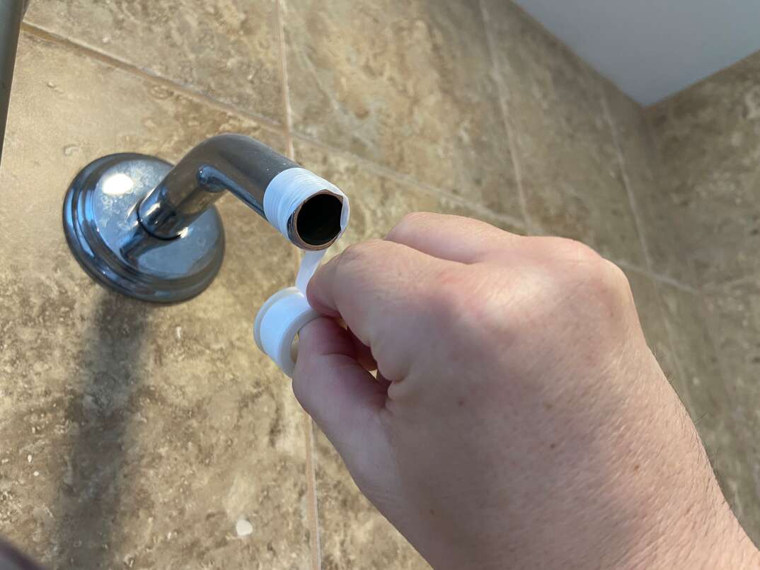 close up image of a new shower head being installed in place of an existing fixture 