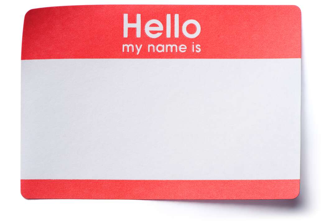 A red and white colored sticky name tag sticker with two opposite corners pulled up has the words Hello My Name Is printed on it as well as a blank space to write your name, red and white colored, red and white, Hello My Name Is, name tag sticker, name tag, tag, sticker, badge, name badge, name change, name