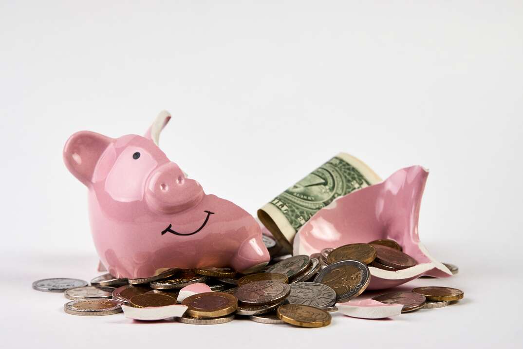 Broken piggy bank with coins money isolated on white background, close-up. Finance, saving money for travel