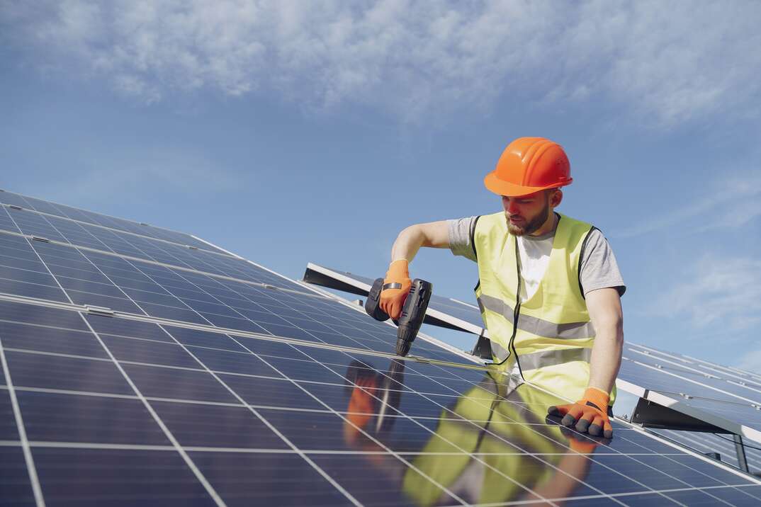 man in organe hardhat installling a solar panel