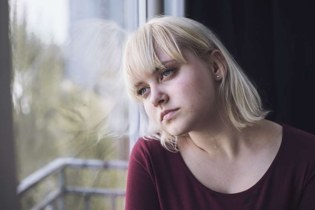 woman staring out of the window while in deep reflection