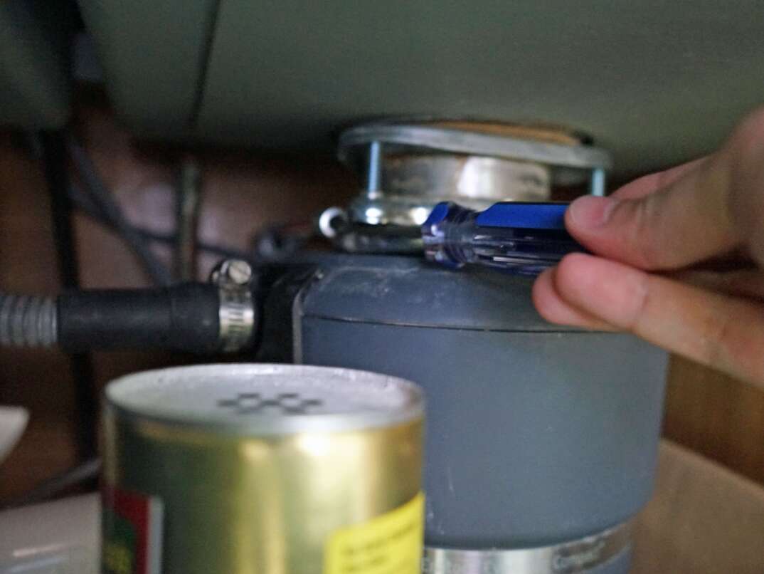 a garbage disposal is removed by using a screwdriver in the provided loops for leverage 