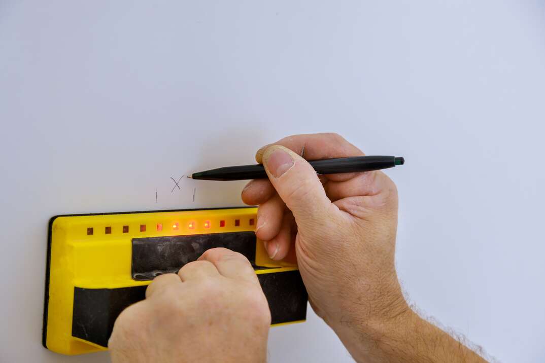 Digital detector man hand is scanning wall by sensors ProSensor precision stud finder wooden beams