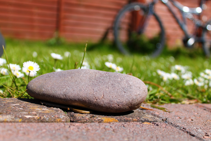 A hidden front door key under a pebble in the garden with a bike in the background