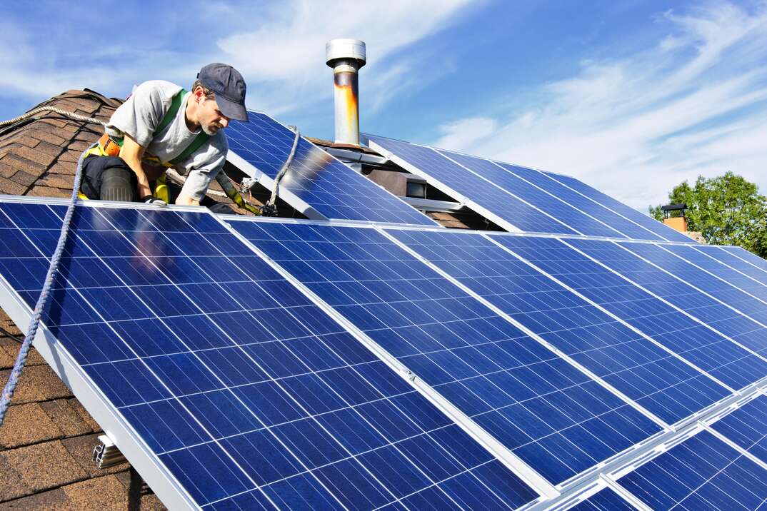 man installing solar panels on roof