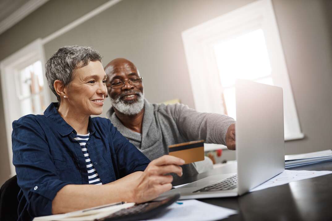 Shot of a senior couple using a credit and laptop while working on their finances at home