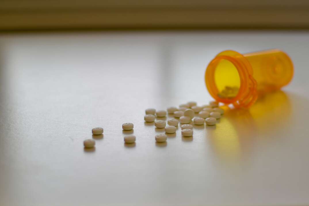 spilled open bottle of pills laying on the floor with pills scattered around