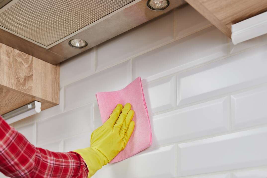 Person cleaning kitchen backsplash