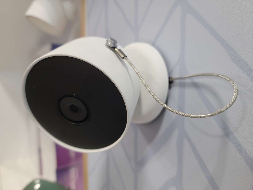Google Nest Cam for outdoor use, colored white with a black face, mounted on a surface.