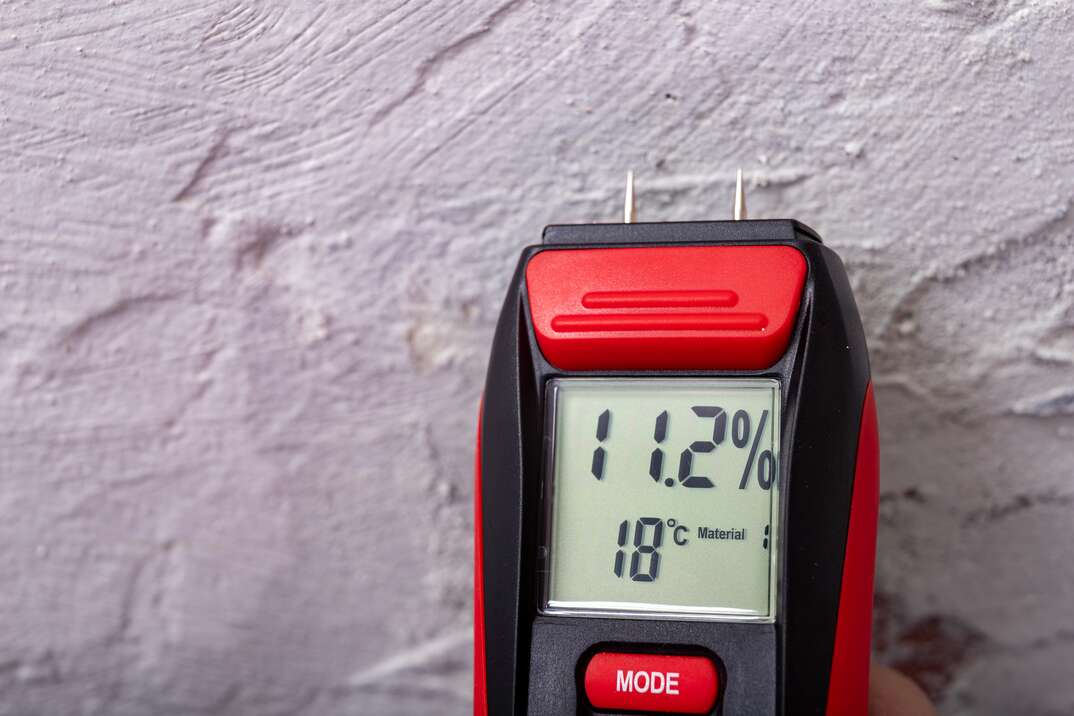 Plaster moisture measurement using an electronic meter. Measurements in the home workshop. Light background.