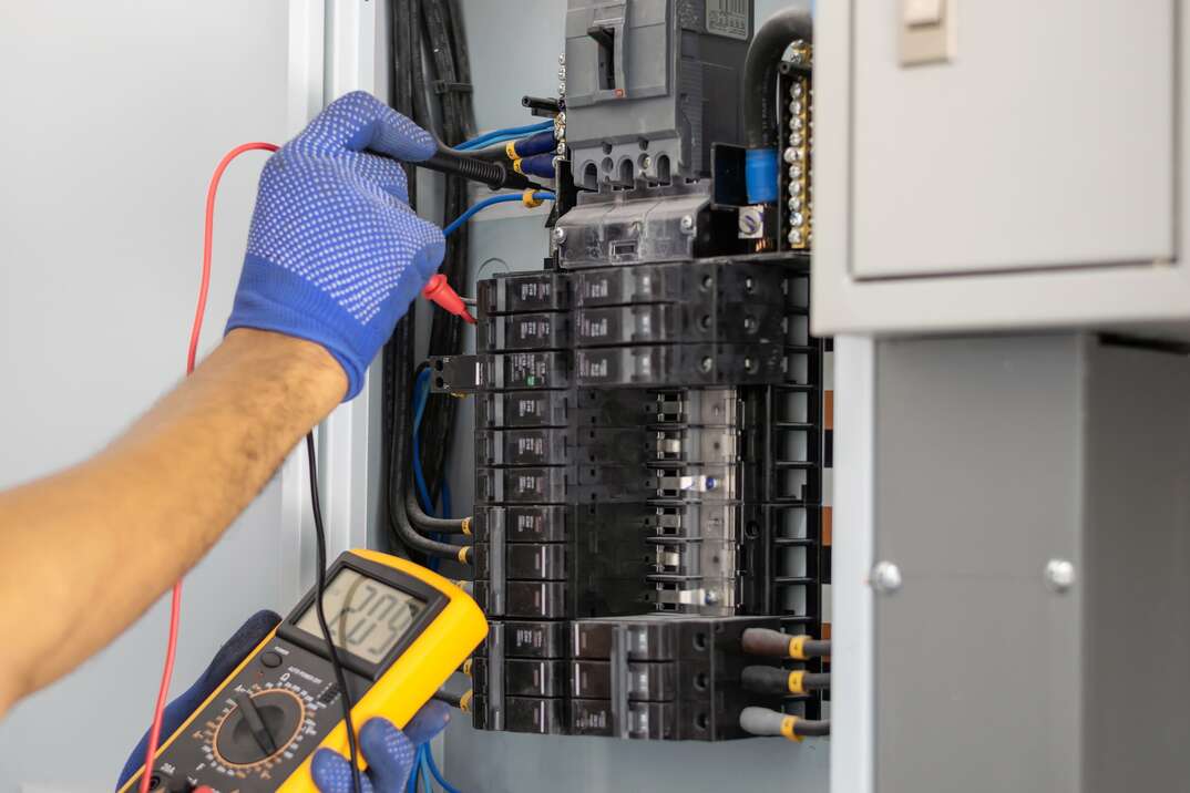 Electrician using a voltage multimeter to test a circuit panel for current