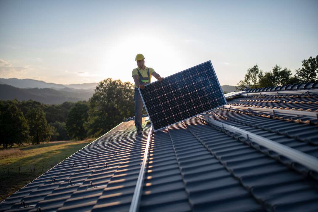Workers Placing Solar Panels On A Roof