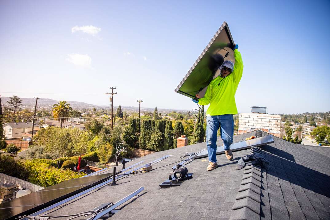 Team of Workers Installing Solar Panels on Residential Rooftop in California