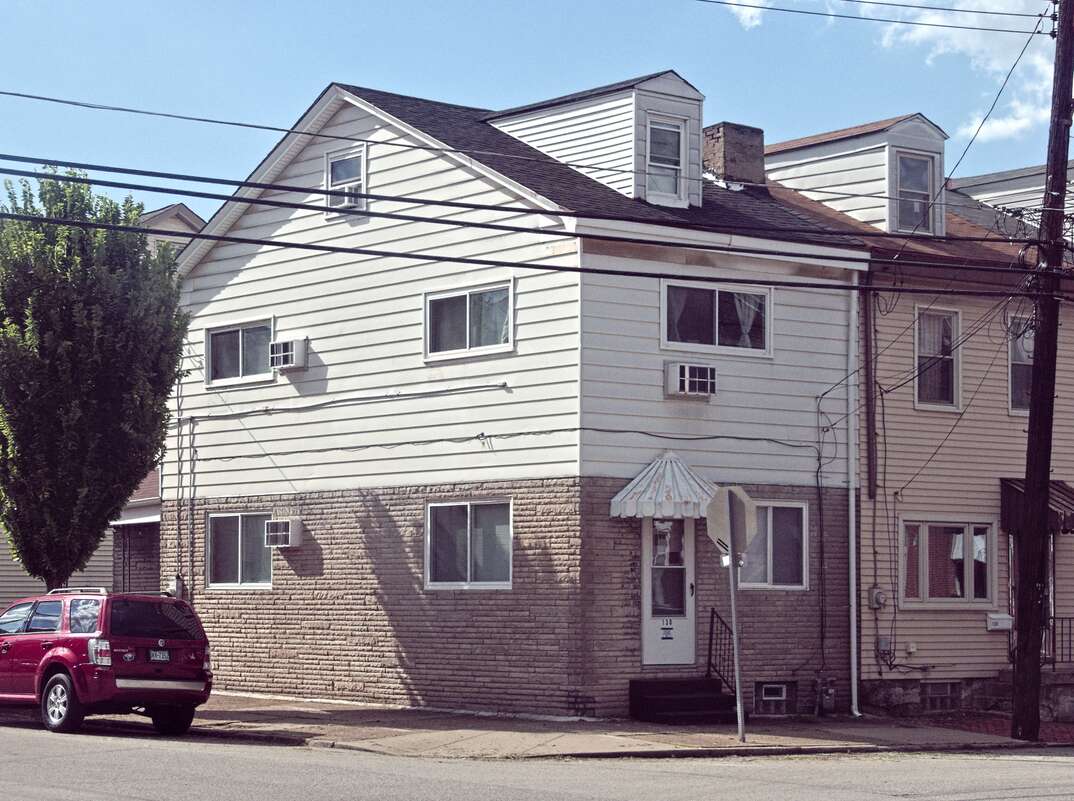 A two-story house is shown with siding covering the exterior walls of the top and brick covering the exterior of the bottom set against a blue sky, house, home, two-story house, two-story home, siding, vinyl siding, vinyl, wood siding, wood, aluminum siding, aluminum, brick wall, brick, wall, walls, street, city street, residential street