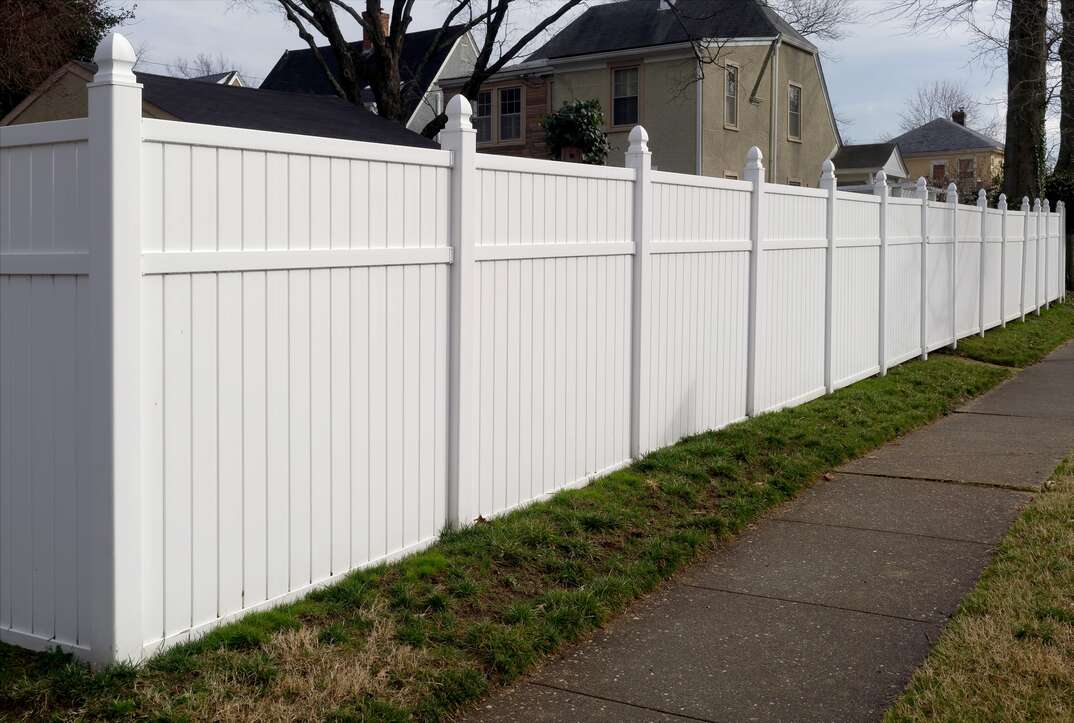 a wide shot of a White Vinyl Fence in a residential neighborhood