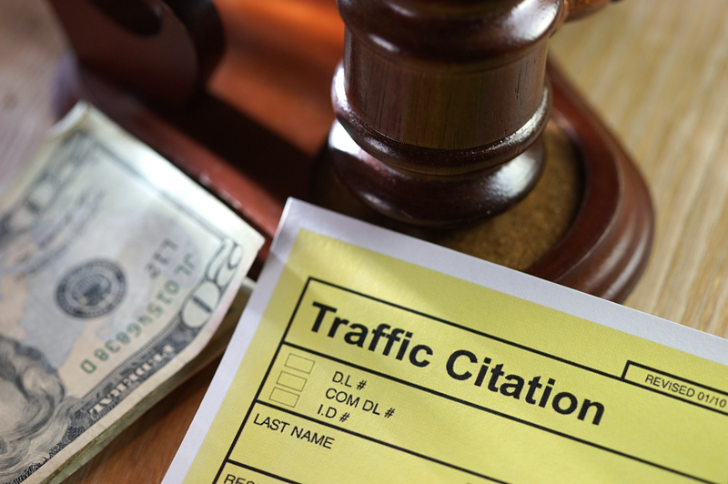 A yellow traffic citation sits next to a twenty dollar bill and the gavel of a judge, gavel, judge's gavel, courtroom, $20, $20 bill, twenty, twenty-dollar bill, cash, cash money, money, traffic ticket, traffic citation, citation, ticket, legal