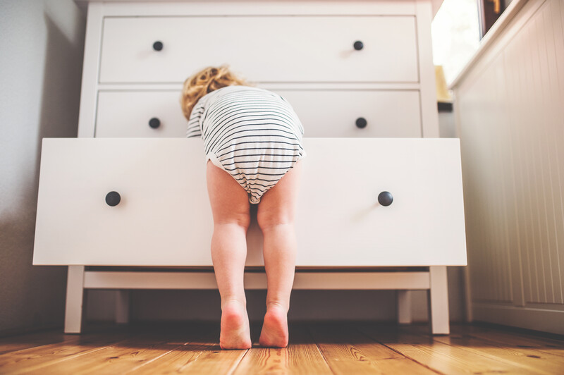 oddler boy in a dangerous situation at home climbing on an open drawer of a white Ikea style dresser, Ikea dresser, Ikea, Ikea furniture, furniture, dresser, dresser drawer, drawer, danger, safety issue, safety, unsafe, toddler, child, youngster, diaper, hardwood floor, hardwood flooring, flooring, floor, hardwood, white dresser