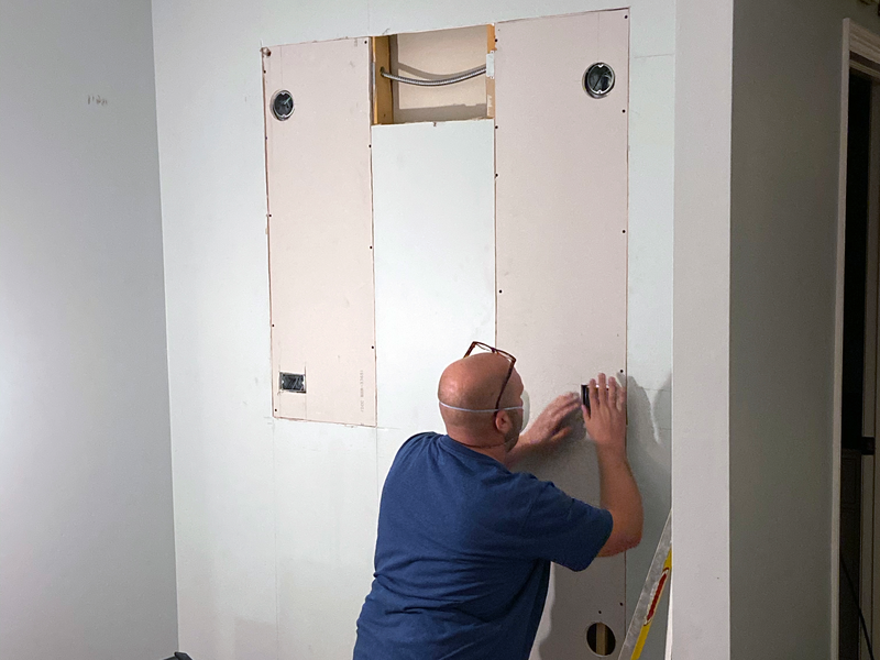 tradesman uses drywall mud or plaster and drywall tape to repair the drywall cuts required by the new electrical work 