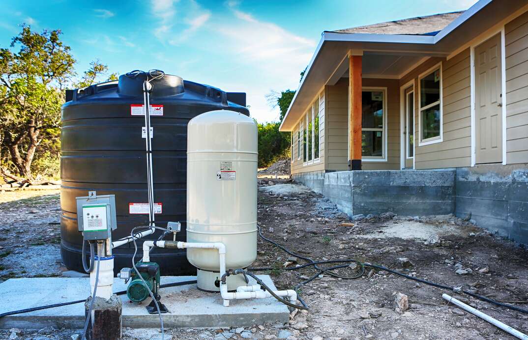 Drilled draw well with pressure switch and storage tank.