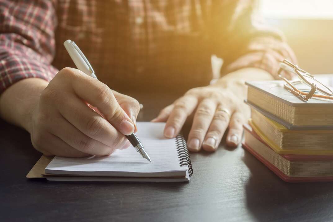 Young male student writes information from portable net-book while prepare for lectures in University campus,hipster man working on laptop computer while sitting in cafe,vintage color,selective focus