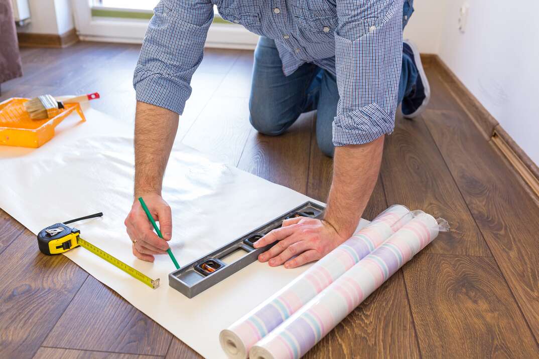 Handyman measuring wallpaper to cut