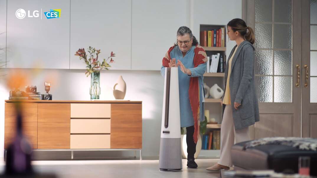 Two women use the LG PuriCare Aero Tower air purifier in a modern living room