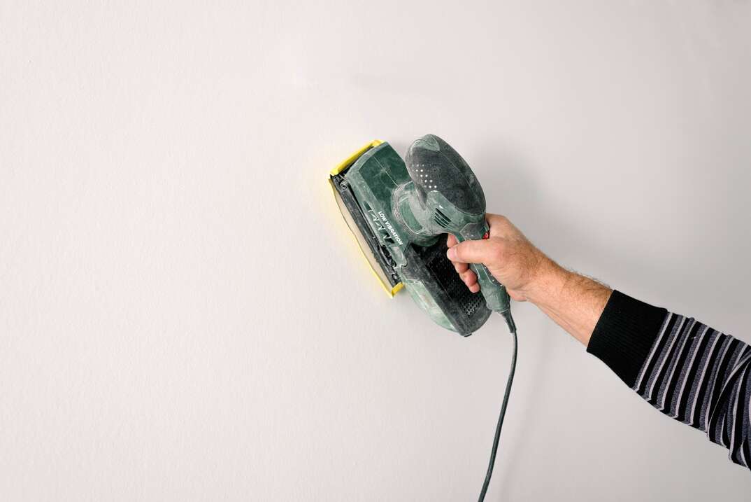contractor sanding white wall