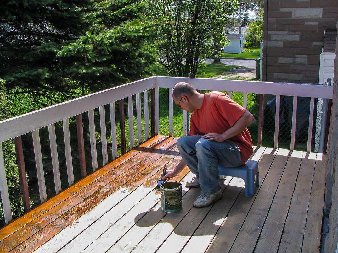 man applying stain to an outdoor wood deck