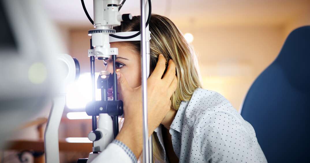 Optometrist examining patient in ophthalmology clinic with professional equipment