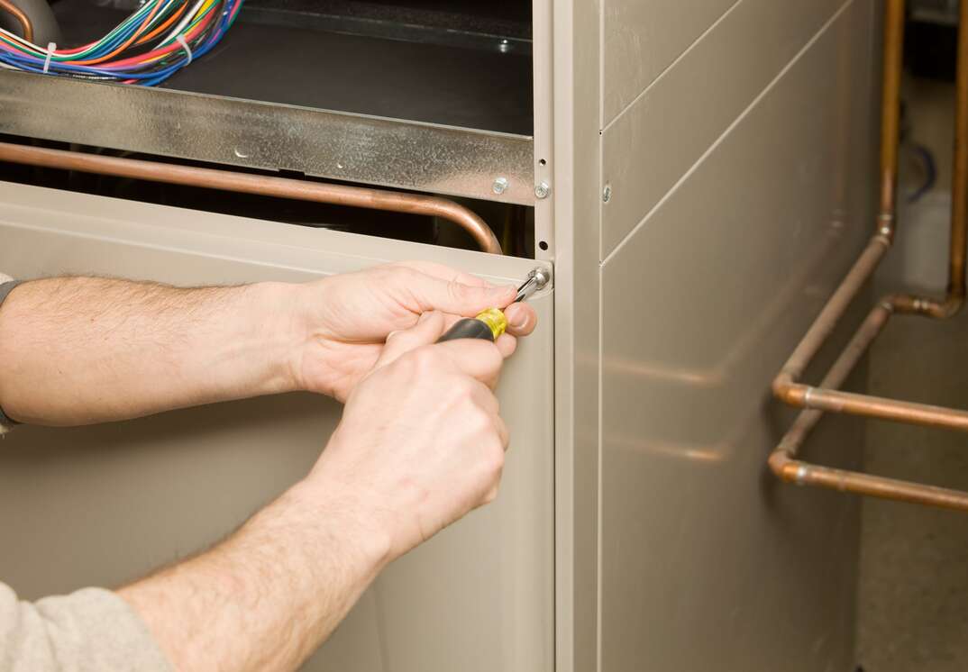 Repair Technician Removing Furnace Service Panel