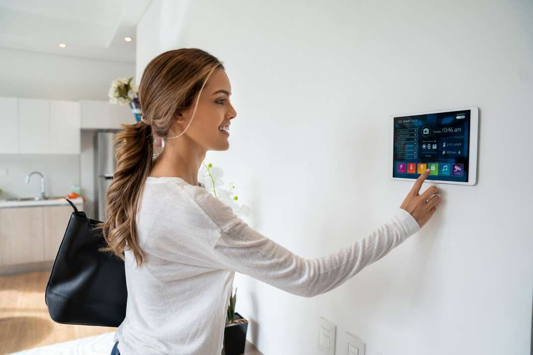 Beautiful woman activating a lock system at her smart home smiling