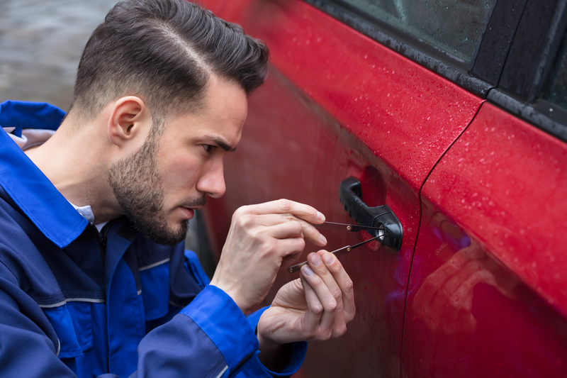 Young Man Opening Red Car Door With Lockpicker
