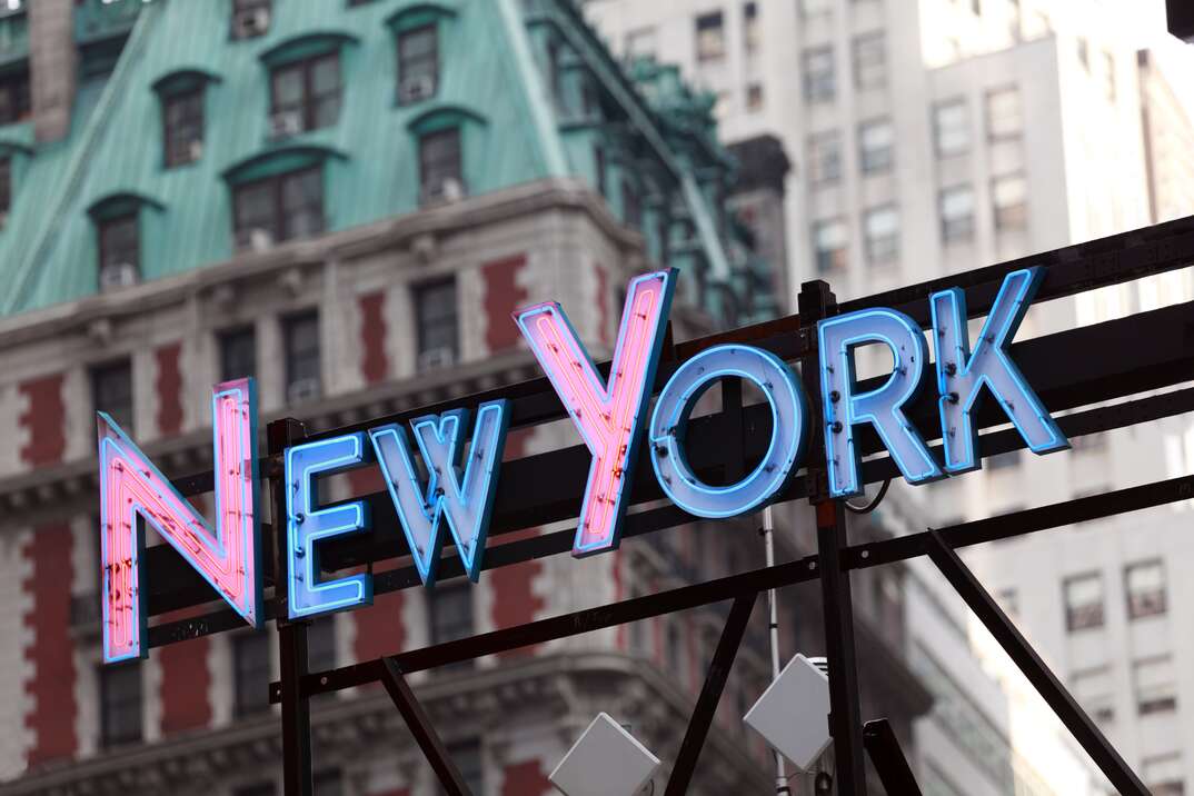 Illuminated New York sign with city buildings in background